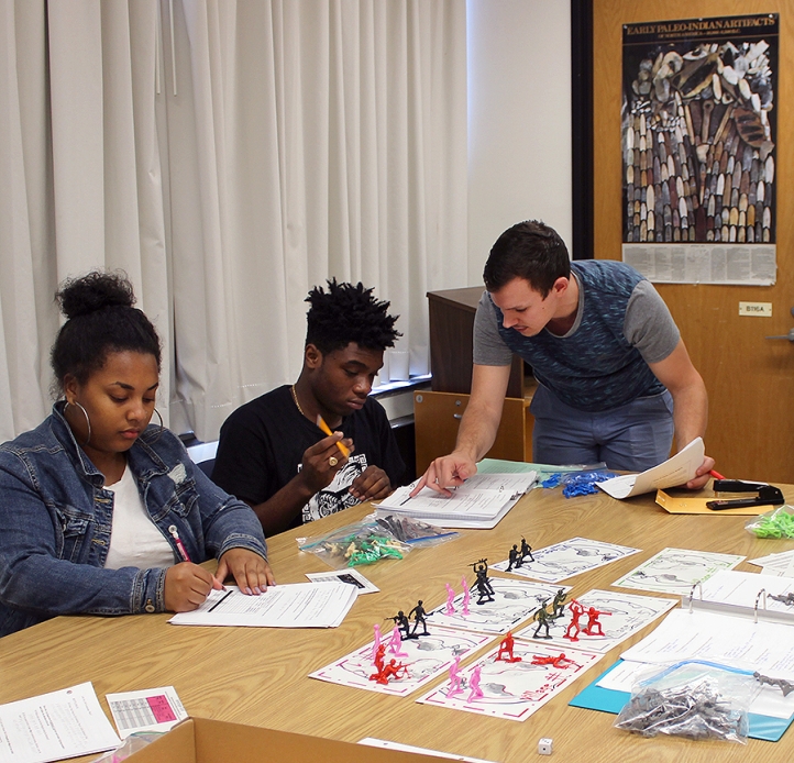 Students at a table with forms and figurines